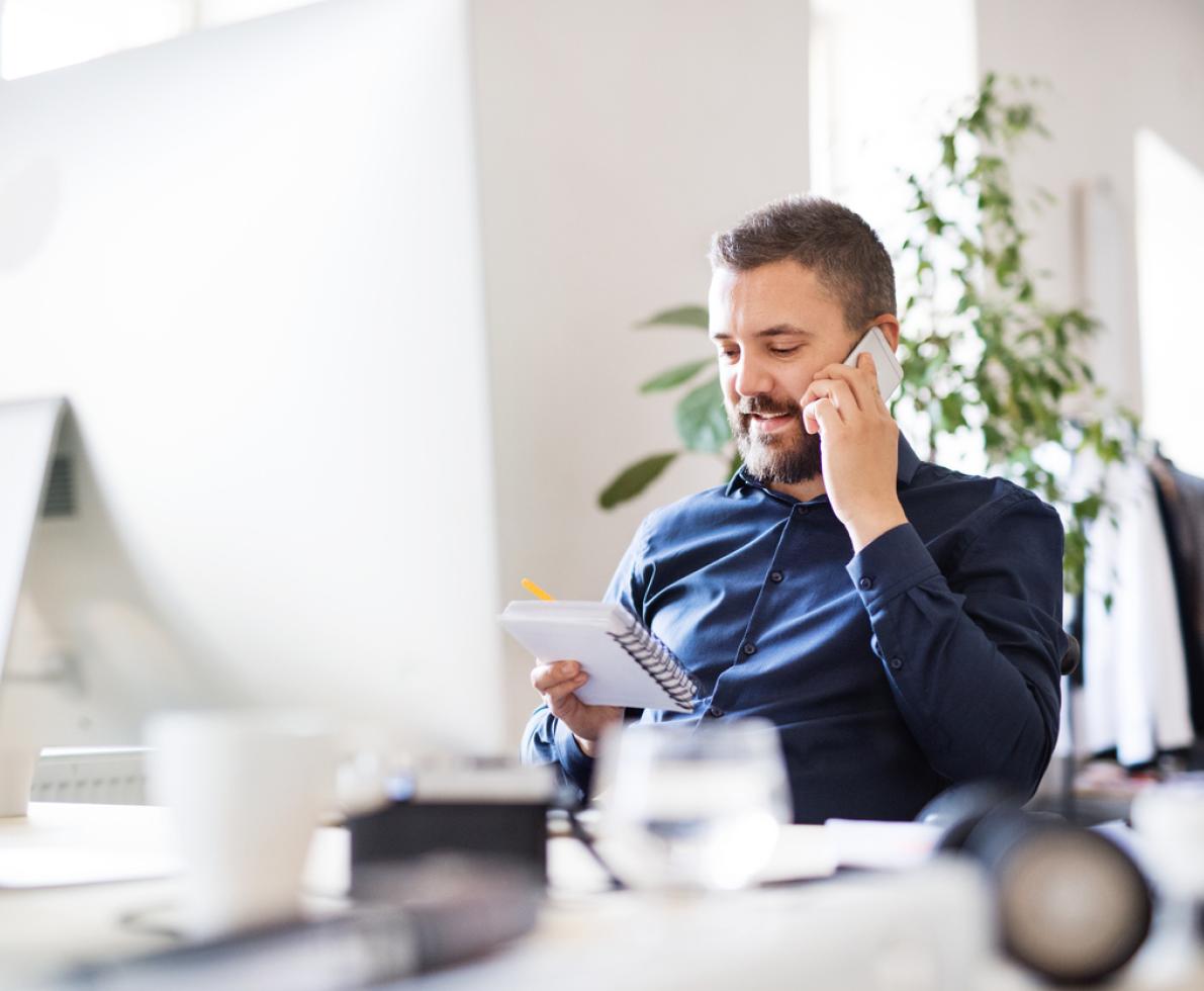 photo of a man making a phone call while sitting at his desk