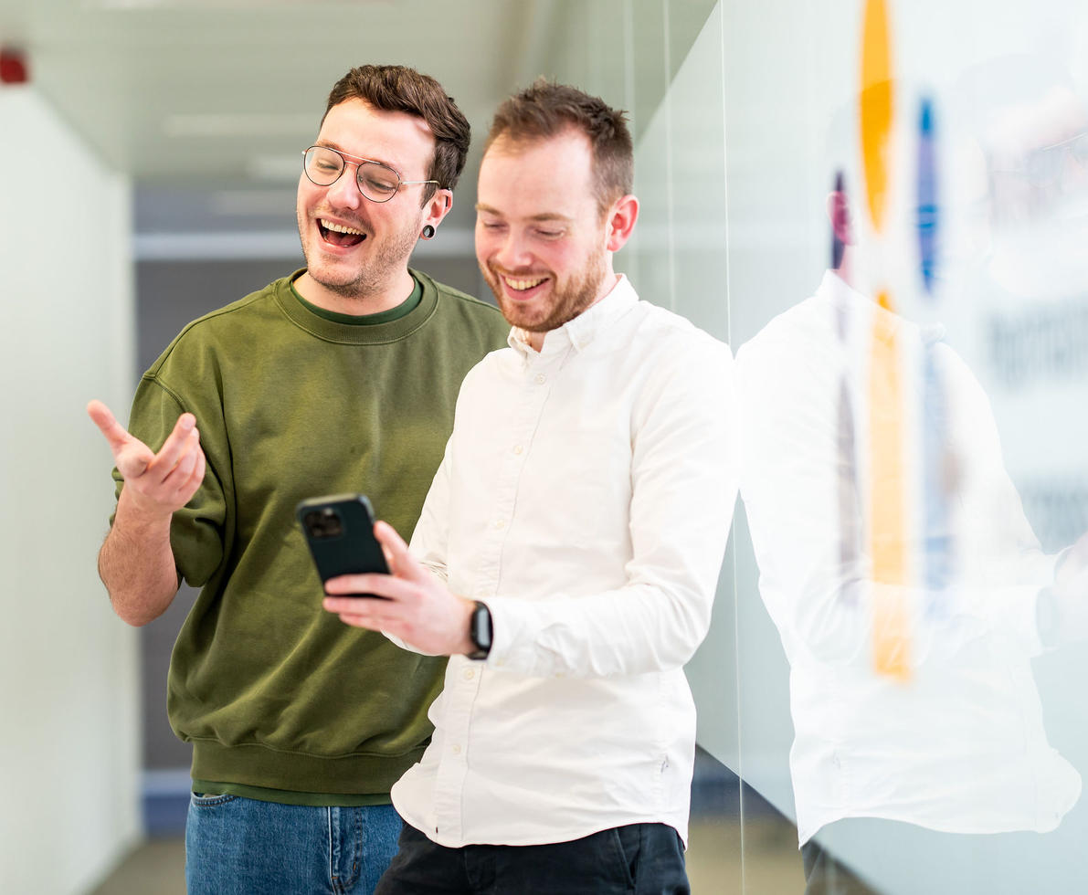 Photo of 2 colleagues, looking at a phone