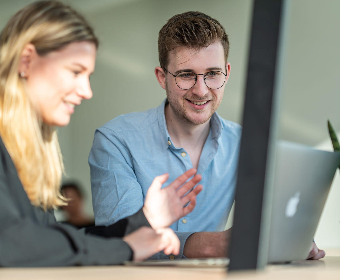 Male and female colleague working on a computer together.